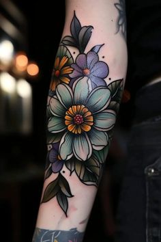 a woman's arm with flowers and leaves tattooed on her forearm, both in blue and yellow