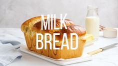 a loaf of bread sitting on top of a white plate next to a bottle of milk