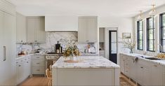 a large kitchen with white cabinets and marble counter tops, along with an island in the middle