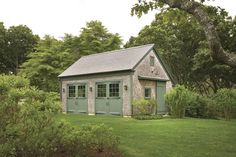 a small shed sitting in the middle of a lush green field next to a tree