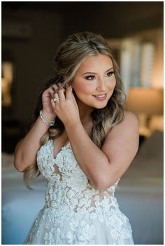 a beautiful woman in a wedding dress holding her hand to her ear