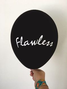 a person holding up a black frisbee with the word fearless written on it