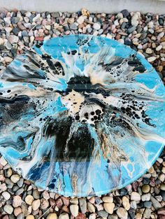 a blue plate sitting on top of a gravel covered ground next to rocks and pebbles