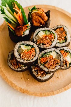 several sushi rolls on a wooden platter with carrots and lettuce