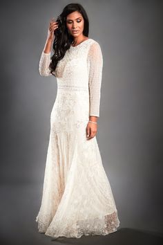 a woman in a long white dress posing for the camera with her hand on her head