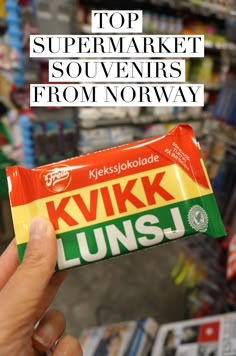 a person holding up a candy bar with the words top supermarket souvenirs from norway