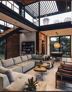 a living room filled with lots of furniture next to a dining table and stairs leading up to an open floor plan