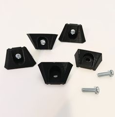 four pieces of black plastic with screws and nuts on a white surface, including one nut