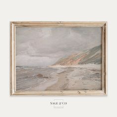 a painting hanging on the wall next to a white frame with an image of a beach