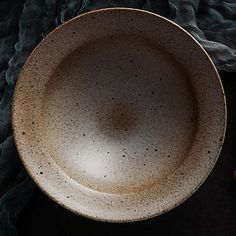 a white bowl sitting on top of a black table cloth next to an orange peel