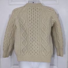 a white mannequin wearing a beige sweater on display in front of a door