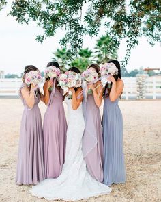 the bridesmaids are holding their bouquets in front of their faces and looking at each other