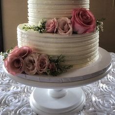 there is a three layer cake with pink flowers on the top and bottom tiers