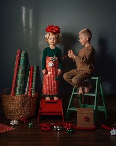 two children are sitting on stools with presents in front of them and one boy is holding a string