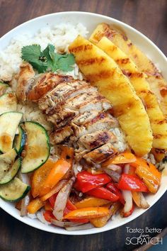 a white bowl filled with meat, vegetables and rice on top of a wooden table