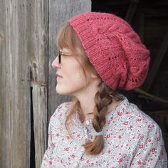 a woman with red hair wearing a pink knitted hat and looking off into the distance