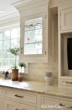 a kitchen with white cabinets and a television on the wall above the counter top,