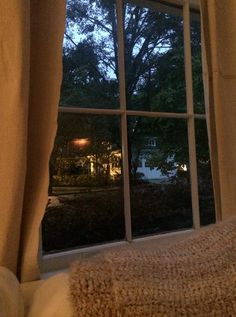 an open window with the view of a tree outside at night in front of it