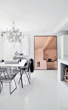 a white dining room with black chairs and a chandelier