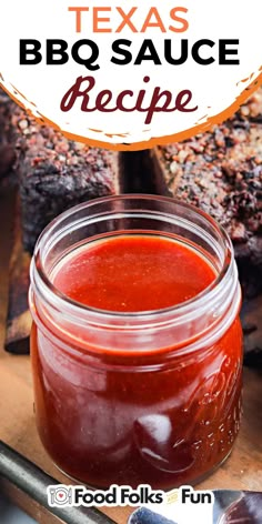 a jar of bbq sauce sitting on top of a cutting board next to ribs