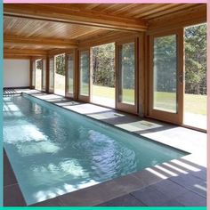 an indoor swimming pool with sliding glass doors leading to the patio and covered in wood