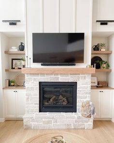 a fireplace with a flat screen tv above it and shelves on the wall behind it