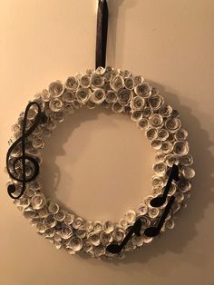 a wreath made out of wine bottle caps hanging on a wall with a black ribbon