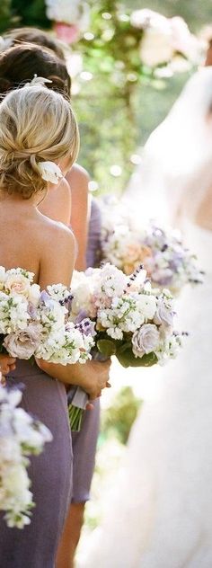 the bridesmaids are holding bouquets of flowers in their hands and looking at each other