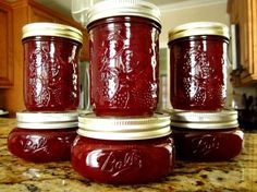 four jars filled with red liquid sitting on top of a counter