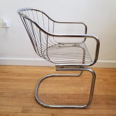 a metal chair sitting on top of a hard wood floor next to a white wall