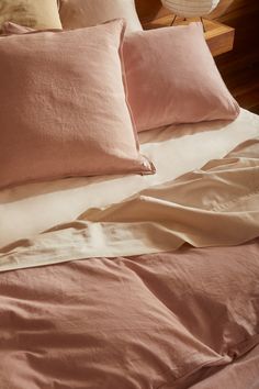 an unmade bed with pink sheets and pillows