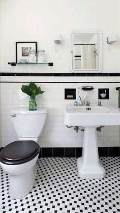 a white toilet sitting next to a black and white sink in a bathroom under a mirror