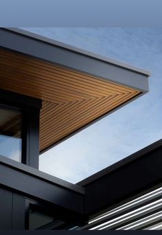 the corner of a building with an open window and sky in the backround