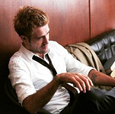 a man sitting on a couch wearing a white shirt and black tie