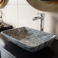 a bathroom sink sitting on top of a wooden counter next to a wall mounted faucet