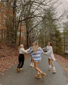 three young women are walking down the road in the woods with their arms around each other