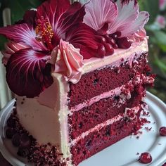 a piece of red velvet cake with white frosting and pink flowers on the top