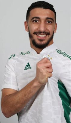 a man with a beard wearing a white shirt and green trimming on his chest