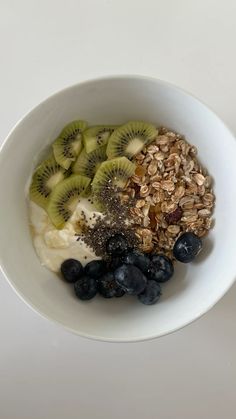 a bowl filled with granola, blueberries and kiwis on top of it