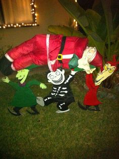 two people dressed as santa claus and the skeleton are dancing in front of a house