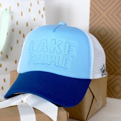 PREMIUM QUALITY: This adjustable strap trucker hat has a tuckaway strap with rust-proof bronze hardware for tightening. The cotton teal brim, aqua teal neoprene upper, white mesh sides, and back are all sewn together to construct the baseball cap. IN-HOUSE DESIGN: The front side of the hat has muted "Lake People" 3D lettering. The side has a sewn-in WP star as well. The breathable construction makes this an awesome statement piece for a relaxed and laid-back day. CARE INSTRUCTIONS: Spot clean on Blue Trucker Hat For Outdoor Activities, Outdoor Blue Mesh Snapback Hat, Blue Mesh Snapback Hat For Outdoor, Adjustable Mesh Blue Hat, Blue Adjustable Mesh Hat, Adjustable Blue Mesh Hat, Blue Trucker Baseball Cap For Outdoor Activities, Blue Baseball Cap For Outdoor, Blue Snapback Trucker Hat For Outdoor Activities