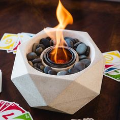 a fire pit sitting on top of a table surrounded by playing cards and dices