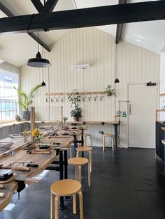 an empty restaurant with tables and stools in the center, along with potted plants on the wall