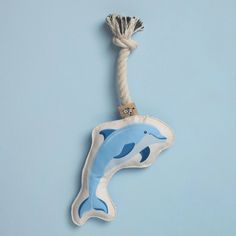 a blue and white dolphin keychain hanging from a rope on a light blue background