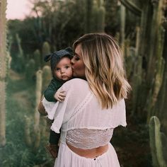 a woman holding a baby in her arms near a cactus field with cacti