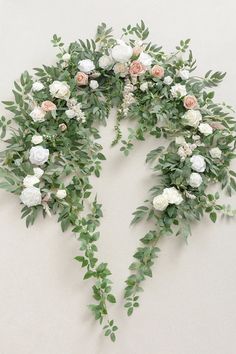 an arrangement of flowers and greenery arranged in the shape of a triangle on a wall