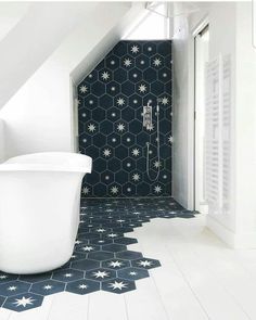 a white bath tub sitting under a bathroom window next to a tiled floor and wall