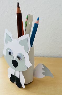 a cup that has some pencils in it and a paper cut out of the shape of a fox