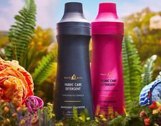 three different types of hair care products sitting in front of some flowers and plants on the ground