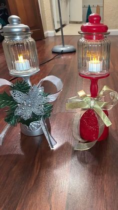 two red candles are sitting on a table next to a small christmas ornament